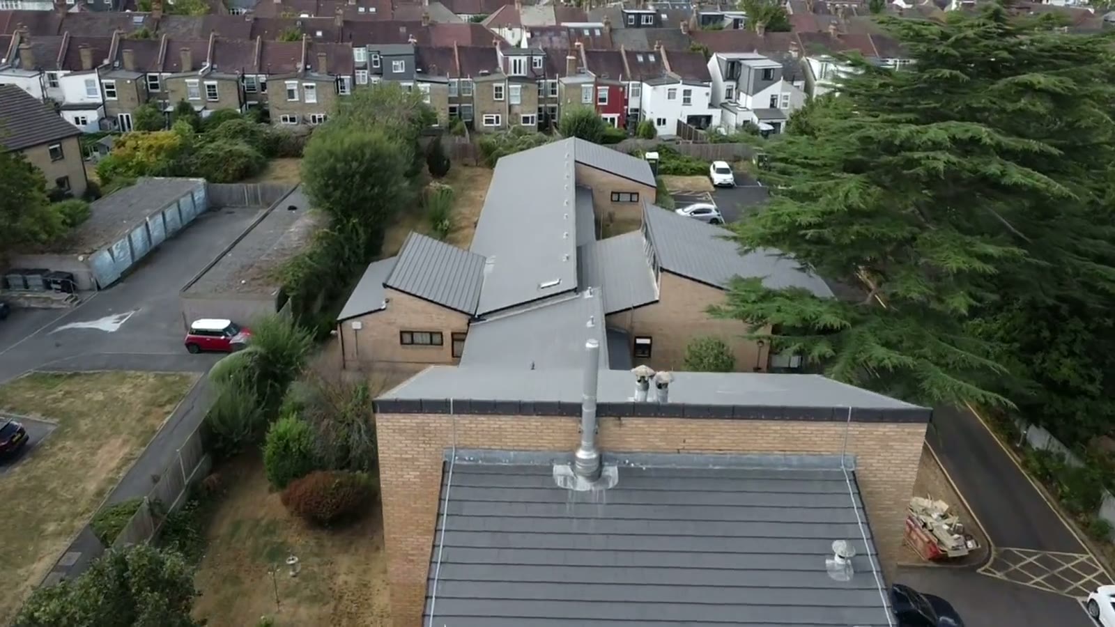 Completed grey standing-seam and slate roofing photographed by drone above a South West property